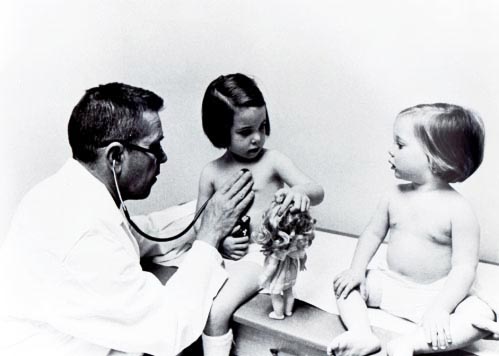 儿科医生约翰·斯迈利和两个小女孩在检查室里