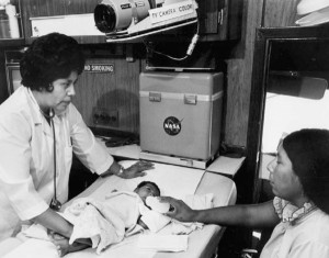 流动医疗单位内的历史黑白照片，医务人员、新生儿患者和母亲