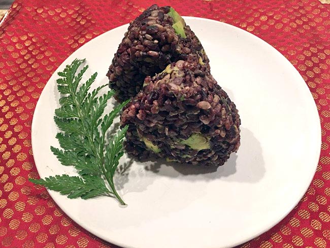 紫黑色的米饭与牛油果块混合，压成三角形。